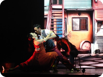 Madero Tango Show in Puerto Madero a tango couple dances with the immigrant tenements as background